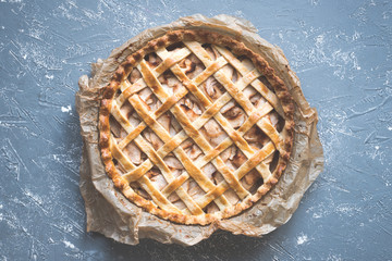 Traditional homemade delicious apple pie on the blue rustic table. Top view