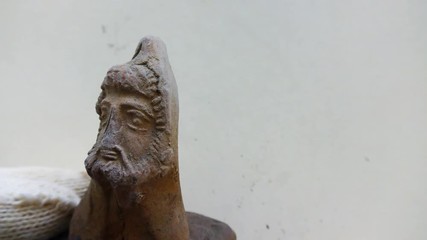 Archeologist inspects tiny ancient authentic clay head - Powered by Adobe