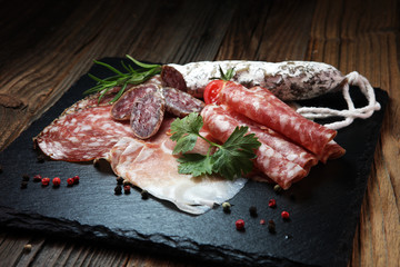 Food tray with delicious salami, ham,  fresh sausages and herbs. Meat platter with selection