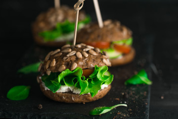 Green sandwich with salad, tomatoes, cucumbers and cream cheese.