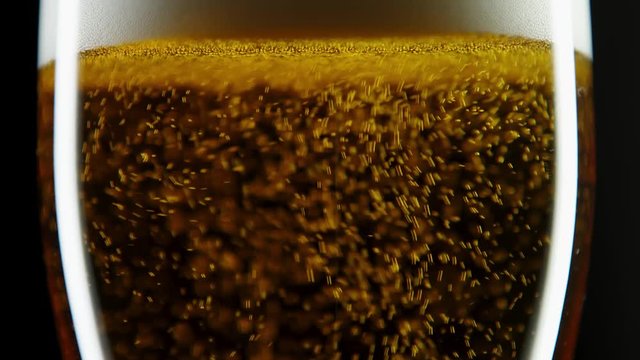 Close up of full beer golden glass being topped up with a splash of beer on a black background with dramatic lighting
