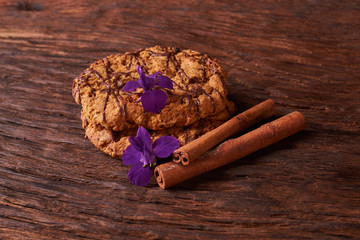 Closeup on stack of chocolate Chip ion wood background with live flowers - cookies for mom on mothers day top view. Selective focus