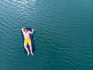 man on mattress in blue water. summer time concept