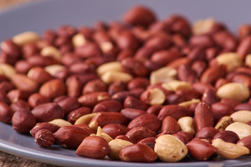 Fried Roasted peanut seed on blue plate on sackcloth background. Space for text. Copyspace