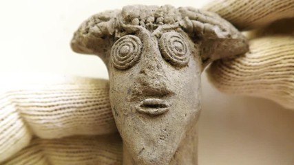 Archeologist inspects tiny ancient authentic clay head - Powered by Adobe