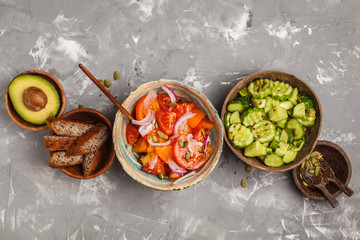 Clean eating concept. Cucumber salad, tomato salad, flax bread, avocado, corn. Top view, food background.