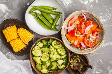 Clean eating concept. Cucumber salad, tomato salad, flax bread, avocado, corn. Top view, food background.