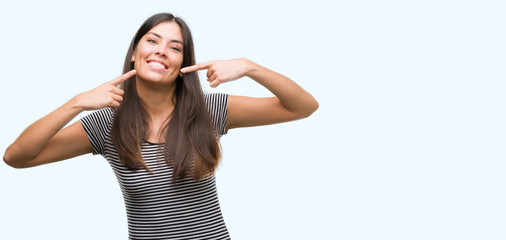 Young beautiful hispanic woman smiling confident showing and pointing with fingers teeth and mouth....