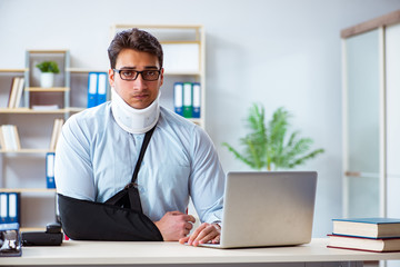 Businessman with broken arm working in office
