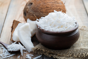 Coconut flakes in a clay bowl on a wooden rustic background