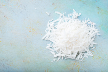 Coconut flakes on a blue background. Top view with copy space