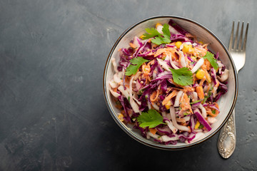 Purple cabbage and carrot salad with mayonnaise in a white bowl on a black background. Classic coleslaw. Diet vegetarian dish. Top view with copy space
