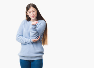 Young Chinese woman over isolated background looking at the camera blowing a kiss with hand on air being lovely and sexy. Love expression.