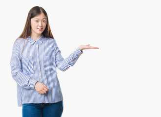 Young Chinese woman over isolated background smiling cheerful presenting and pointing with palm of hand looking at the camera.