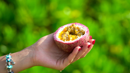 Passion fruit cut in half in woman's hand