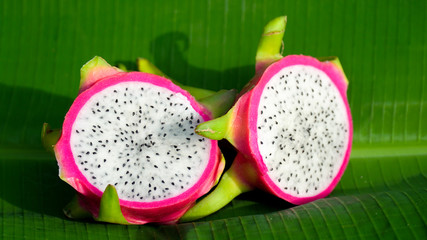 Dragon fruit cut in half on a green leaf