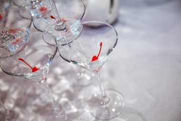Empty Martini glass with cocktail cherry is built in the form of a pyramid.