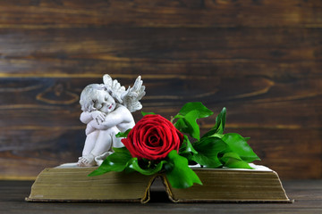 Condolence card with sleeping angel and red rose on open book