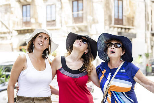 Three women looking up on the street