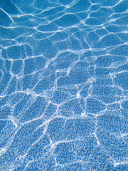 Blue pool bottom liner with ripples caused by sunlight