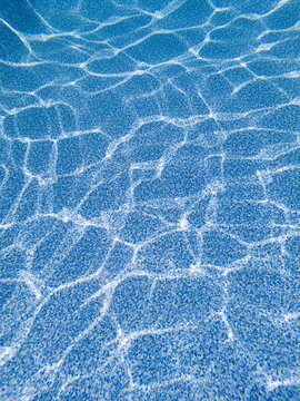 Blue pool bottom liner with ripples caused by sunlight