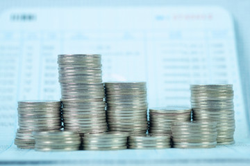 Step of coin stack with passbook or account book on wooden working table, savings and banking...