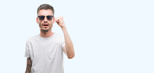 Young tattooed adult man wearing sunglasses annoyed and frustrated shouting with anger, crazy and yelling with raised hand, anger concept