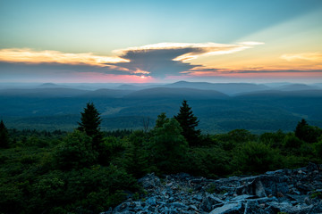 Obraz na płótnie Canvas The sun sets behind a giant thunderstorm cloud in the Appalachian Mountains seen from Spruce Knob in West Virginia