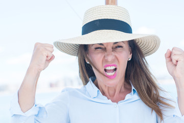 Beautiful middle age woman traveling on sailboat annoyed and frustrated shouting with anger, crazy and yelling with raised hand, anger concept