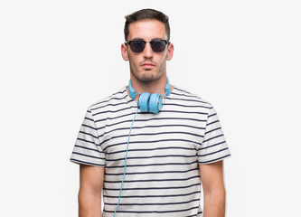 Handsome young man wearing headphones with serious expression on face. Simple and natural looking at the camera.
