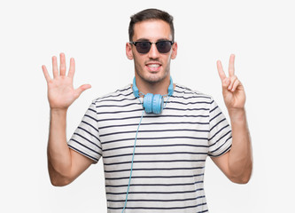 Naklejka premium Handsome young man wearing headphones showing and pointing up with fingers number seven while smiling confident and happy.