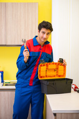 Plumber repairing tap at kitchen