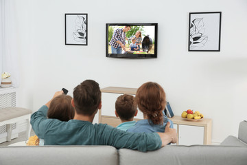 Family watching TV on sofa at home