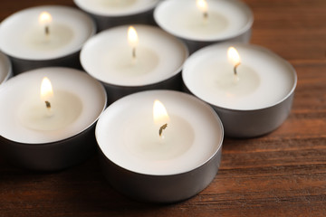 Fototapeta na wymiar Small wax candles burning on wooden table, closeup