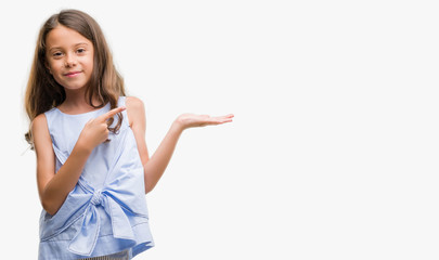 Brunette hispanic girl amazed and smiling to the camera while presenting with hand and pointing with finger.