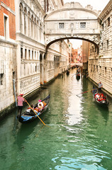 Gondolier transportant des touristes dans leur gondole, par le pont des soupirs à Venise, Italie au coucher du soleil