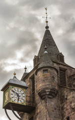 Fototapeta na wymiar Edinburgh, Scotland, UK - June 12, 2012: Closeup of the clock tower of Brown stone People’s Story Museum under heavy stormy sky. Previously Tolbooth.