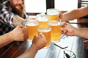 Friends clinking glasses with beer in pub