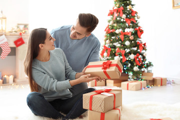 Young man giving Christmas gift to his girlfriend at home