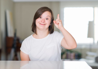 Down syndrome woman at home surprised with an idea or question pointing finger with happy face, number one