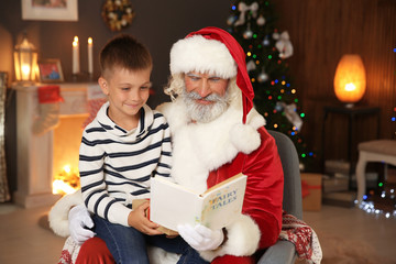 Fototapeta na wymiar Little child with Santa Claus reading Christmas story at home