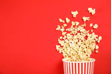 Schilderijen op glas Paper cup with tasty fresh popcorn on color background, top view © New Africa