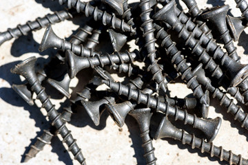 Closeup macro image of unused black carpenter wood screws with strong shadows and copyspace area for woodwork carpentry based designs and indeas