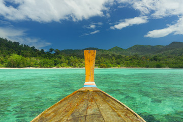 A wooden boat sails to a tropical island.