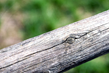 Macro image of a worn aged wooden post with a defocused green vegetation background