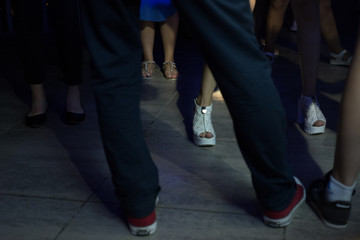 Fototapeta premium Peoples feet and legs dancing at a nightclub with diffrerebt color lights and smoke effects with no faces