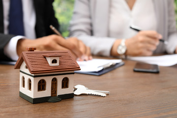 Keys and house model on table in real estate agent's office