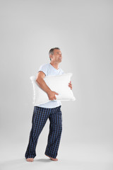 Man holding soft pillow on light background