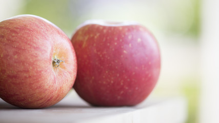 Apples on a wooden cutting board in front of an open door.  Bright sunny day.