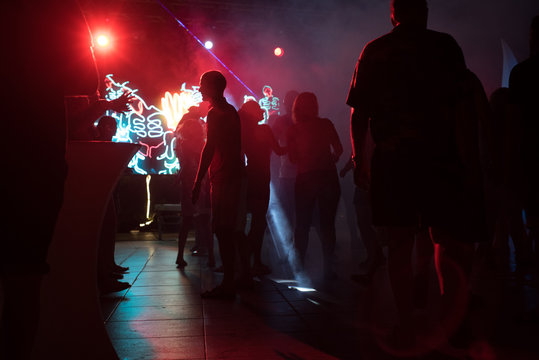 People dance at a nightclub at night in silhouette with different color lights and digital effects
